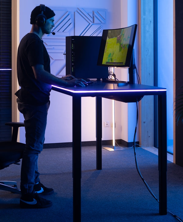 Gamer spielt im Stehen am Desk Four von Yaasa mit LED Tischbeleuchtung in einem dunklen Raum