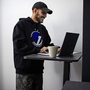 Mann arbeitet im Stehen am schwarzen Yaasa Desk One mit einem Laptop