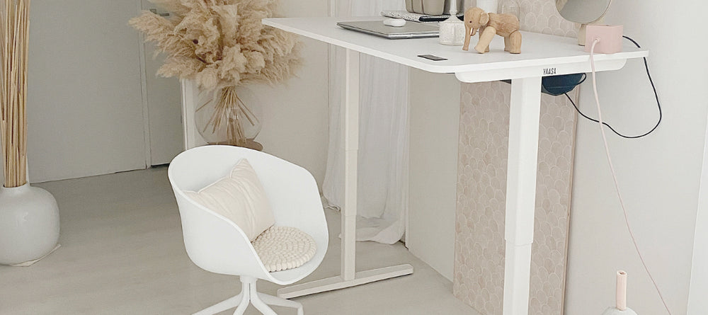 Weißer Yaasa Desk Pro 2 in Stehposition mit einem weißen Stuhl in einem hellen Wohnraum