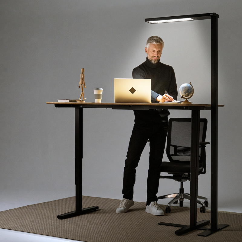 YAASA Lamp Expert noire éclairant un bureau réglable en hauteur avec une personne travaillant debout.