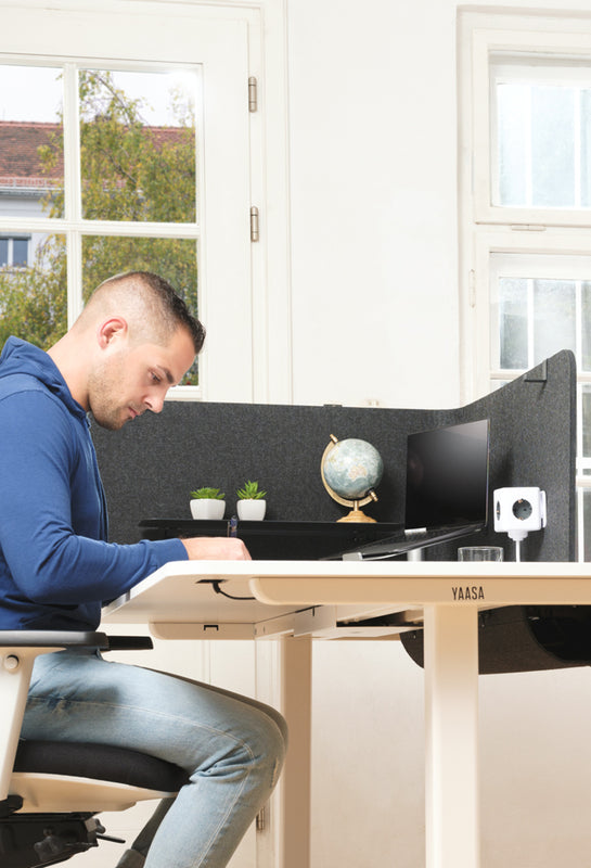 Mann arbeitet im Sitzen an einem Schreibtisch mit Yaasa Privacy Wall und Yaasa Privacy Wall Accessory Kit