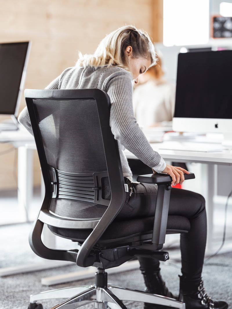 Frau sitzt auf einem ergonomischen Bürostuhl im Büro