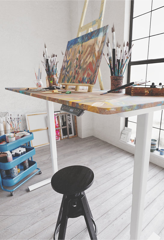 Yaasa Desk Frame in ausgefahrener Position mit einer künstlerischen Tischplatte in einem Atelier 