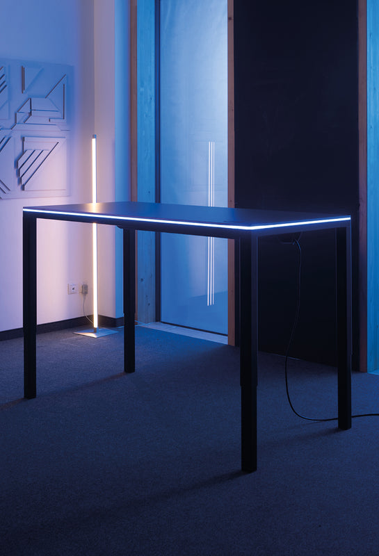 Desk Four Dunkelgrau/Schwarz mit Yaasa LED Tischbeleuchtung in einem dunklen Raum