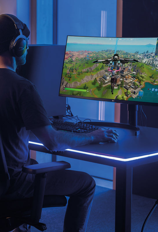 Gamer sitzt am Desk Four mit Yaasa LED Tischbeleuchtung in einem dunklen Raum