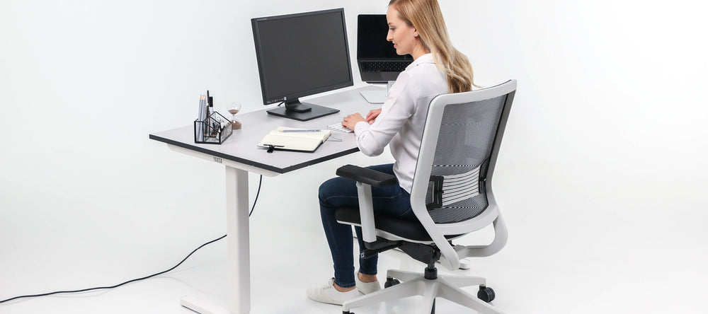 Frau arbeitet im Sitzen am Yaasa Desk Basic in Silberweiß